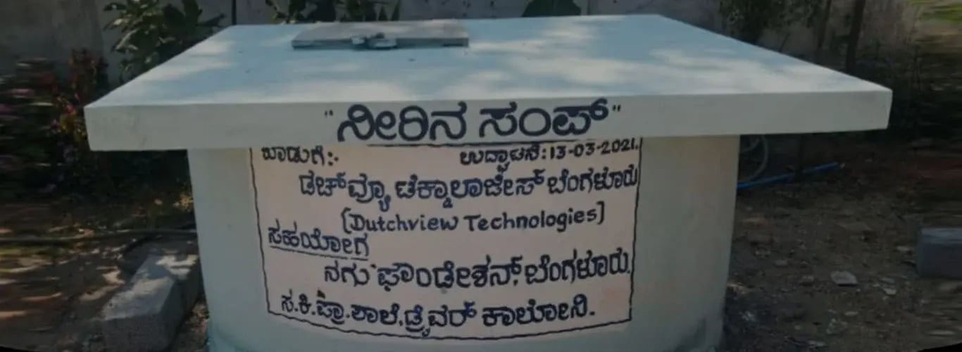 Water tank at a government primary school in Karnataka with a sign in Kannada naming Dutchview Technologies and NAGU Foundation